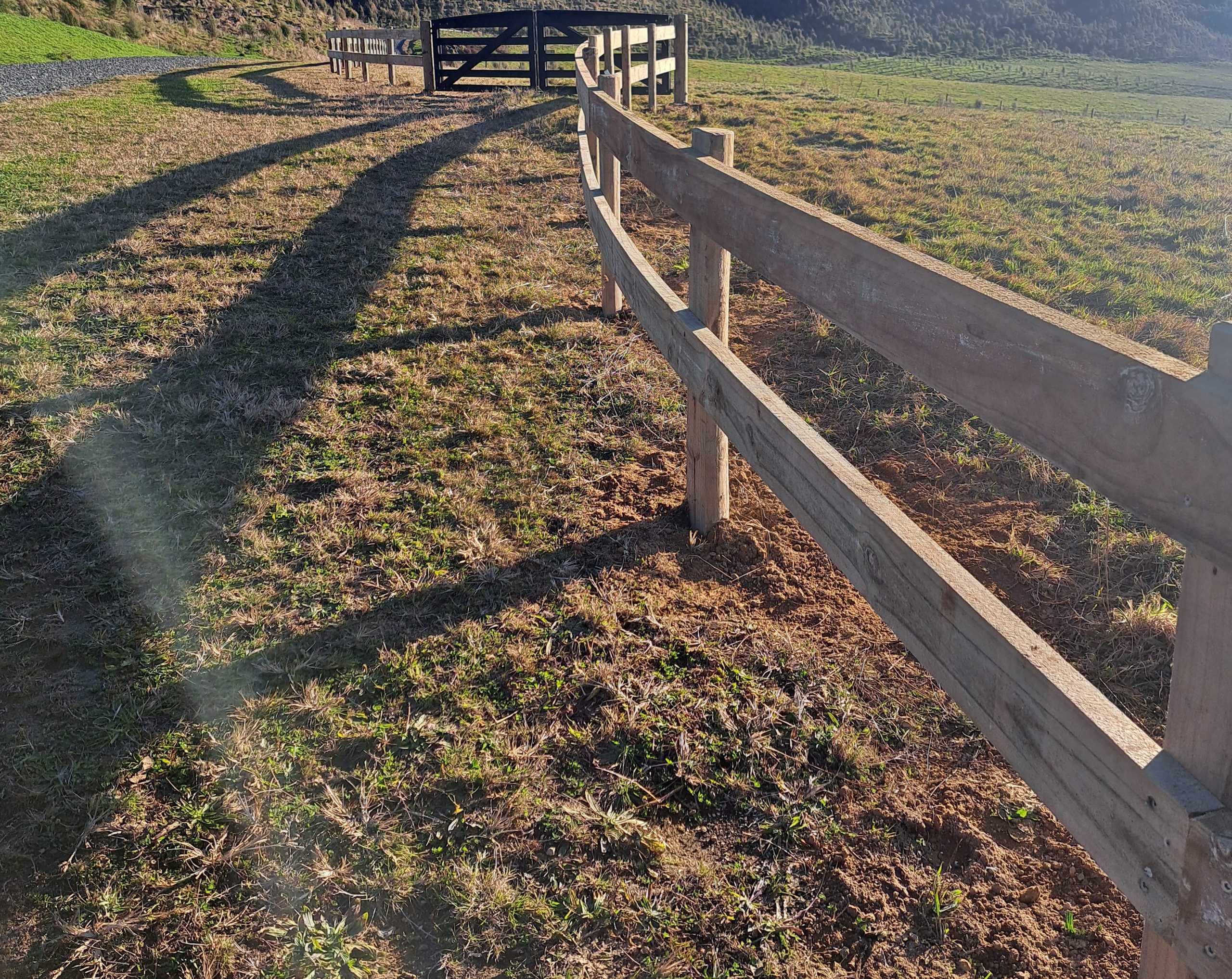 Curved rail fence that goes to hanging gate